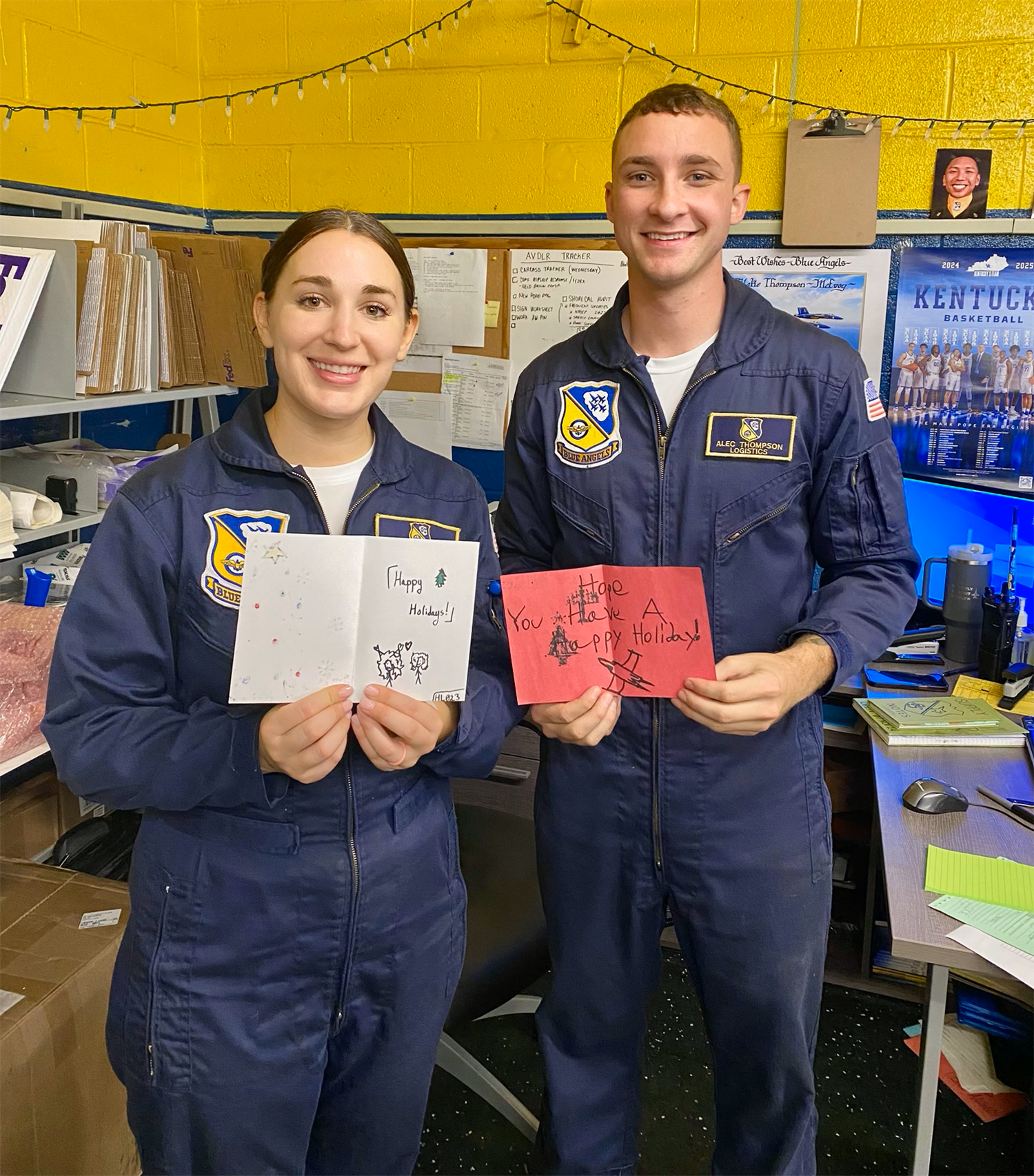 Members of the Blue Angles Squadron holding Christmas cards made by students.